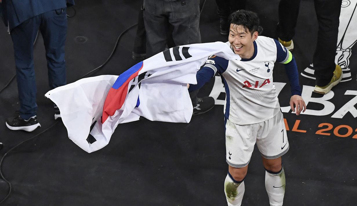 Pemain Tottenham Hotspur, Son Heung-min menangkap bendera Korea Selatan yang dilemparkan oleh penonton setelah laga final Liga Europa 2024/2025 melawan Manchester United di Stadion San Mames, Bilbao, Spanyol, Kamis (22/05/2025) WIB. (AFP/Ander Gillenea)