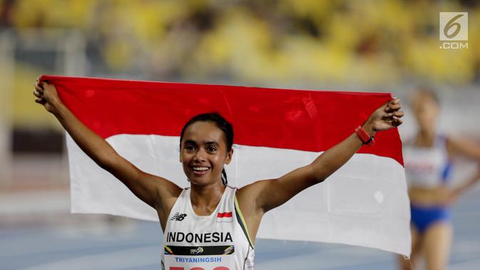 Pelari Indonesia Triyaningsih membawa bendera merah putih setelah mencapai garis finis dalam cabang olahraga atletik nomor lari 10 km putri SEA Games 2017 di Stadion Nasional Bukit Jalil, Malaysia, Kamis (24/8). (Liputan6.com/Faizal Fanani)