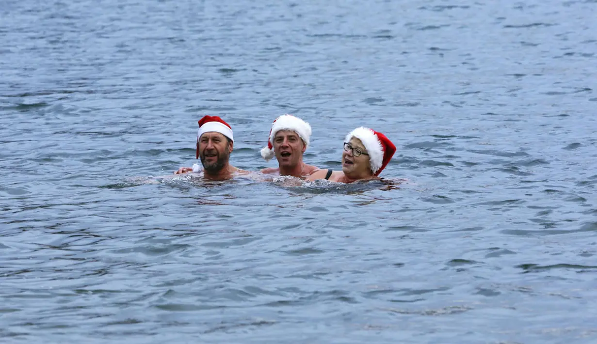 Puluhan anggota klub renang "Berliner Seehunde" merayakan Natal dengan berenang di danau Orankesee, Berlin (25/12/2014). Anggota klub "Berliner Seehunde" bernyanyi saat berenang di danau Orankesee, Berlin. (REUTERS/Fabrizio Bensch)