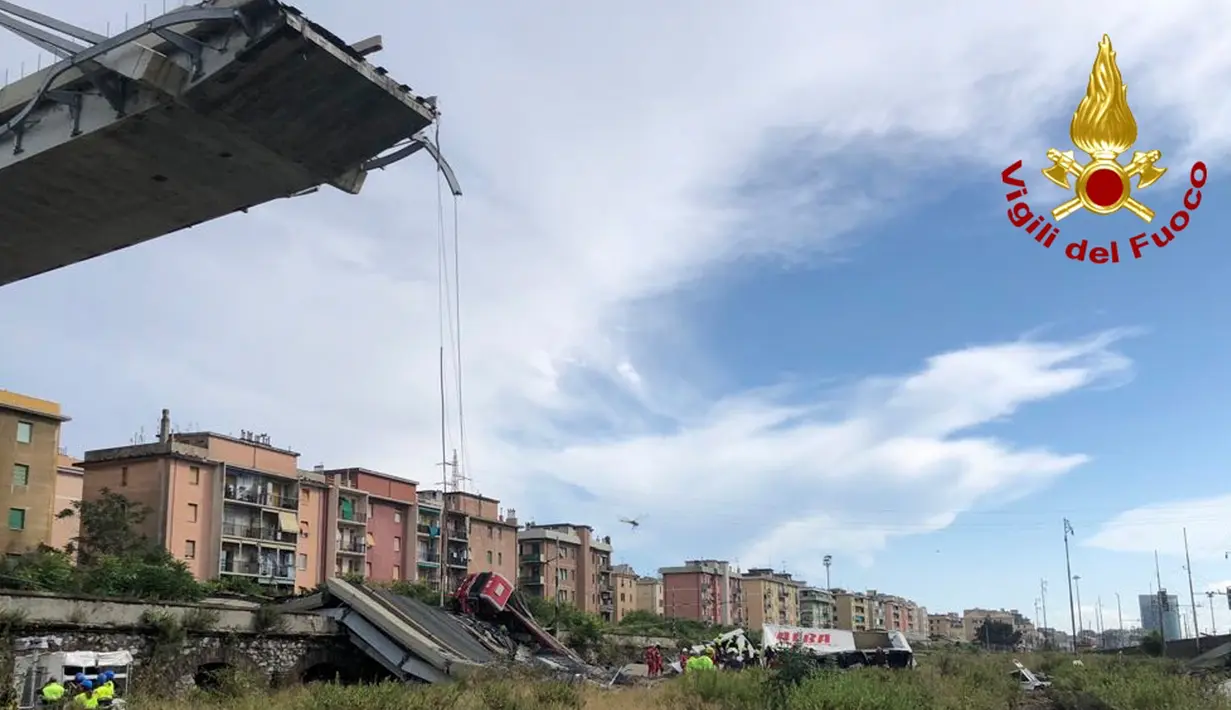 Tim penyelamat berada di antara puing-puing jembatan jalan raya Morandi yang ambruk di kota Genoa, Italia, Selasa (14/8). Mobil-mobil jatuh dari jembatan serta puing-puing tiang ke arah rel kereta. (Vigili Del Fuoco via AP)