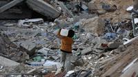 Saat ini jutaan anak masih menghadapi masalah-masalah yang sering membuat mereka merasa terancam hingga menimbulkan rasa takut. Tampak dalam foto, seorang anak laki-laki Palestina membawa sebuah wadah plastik saat dia berjalan melewati puing-puing di samping sebuah bangunan yang hancur akibat pemboman Israel baru-baru ini di Khan Yunis di Jalur Gaza selatan pada 19 November 2024. (Eyad BABA/AFP)