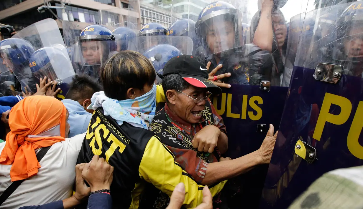 Pengunjuk rasa terlibat bentrok dengan polisi saat menggelar aksi demo di dekat Kedutaan Besar AS di Manila, Filipina (11/11). Mereka menggelar aksi untuk memprotes kunjungan Presiden AS, Donald Trump ke Filipina. (AP Photo/Aaron Favila)