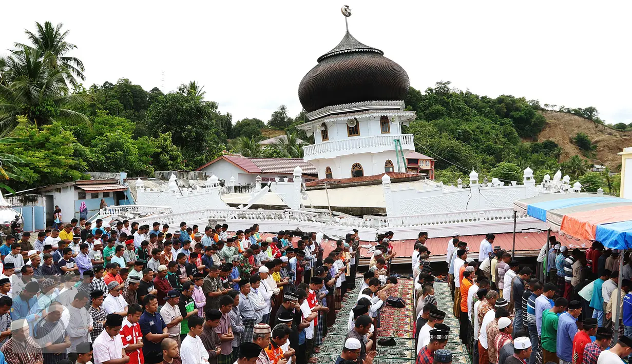 Sejumlah warga melaksanakan Salat Jumat di halaman Masjid Jami Quba, Pidie Jaya, Aceh, Jumat (9/12). Gempa berkekuatan 6,5 SR telah merobohkan ratusan bangunan termasuk Masjid Jami Quba. (Liputan6.com/Angga Yuniar)