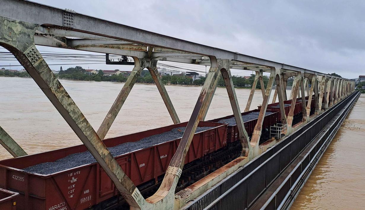 Gerbong kereta api diparkir di jembatan kereta api untuk mengamankan struktur jembatan agar tidak hanyut oleh banjir di Hue, Vietnam, Selasa, 28 Oktober 2025. Hujan deras yang mengguyur kawasan pesisir tengah Vietnam sejak akhir pekan lalu, membuat sekolah-sekolah ditutup dan bekas ibu kota kekaisaran Vietnam, Hue, yang merupakan situs warisan dunia UNESCO, terendam air. (Nguyen Van Ly/VNA via AP)