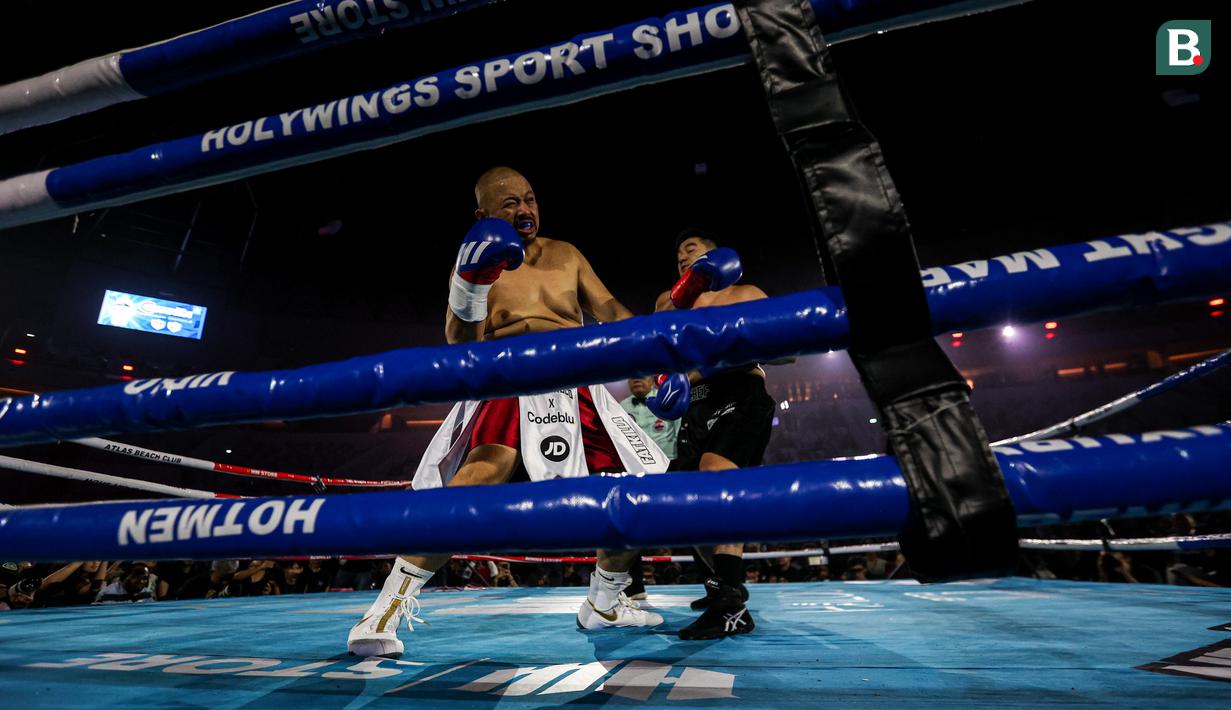 Konten kreator Codeblue (kiri) terkena pukulan dari Chef Arnlod dalam pertarungan tinju Holywings Sports Show (HSS) seri kelima di Indonesia Arena, Kompleks Stadion Utama Gelora Bung Karno, Senayan, pada Minggu (22/04/2024). (Bola.com/Bagaskara Lazuardi)