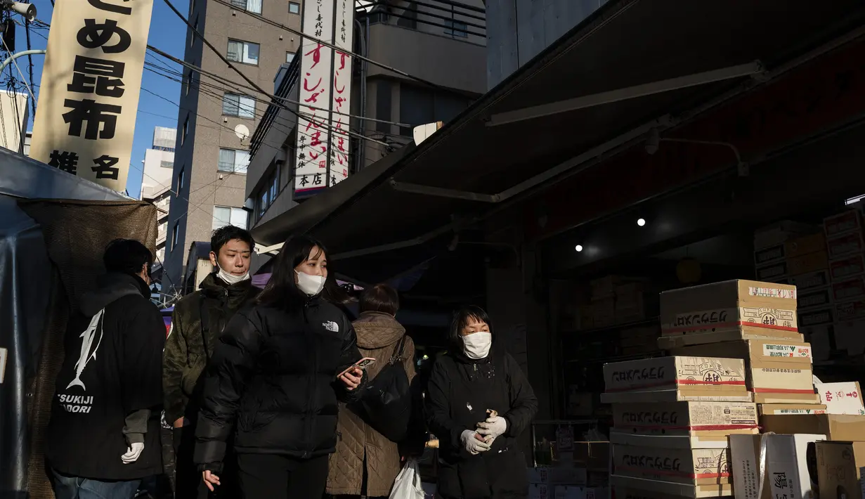 Orang-orang berjalan melalui jalan di area "pasar ikan luar" Tsukiji di Tokyo pada 28 Desember 2022. Menjelang liburan Tahun Bar, turis asing dan penduduk lokal berkunjung  ke pasar itu untuk menikmati hidangan bermacam makanan laut. (AFP/Richard A. Brooks)