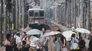 Peringatan cuaca panas ekstrem telah dikeluarkan di 44 dari total 47 prefektur di Jepang. Tampak dalam foto, kabut panas terlihat di latar belakang saat pejalan kaki dengan payung melintasi rel kereta api di Tokyo pada 5 Agustus 2025. (Kazuhiro NOGI/AFP)