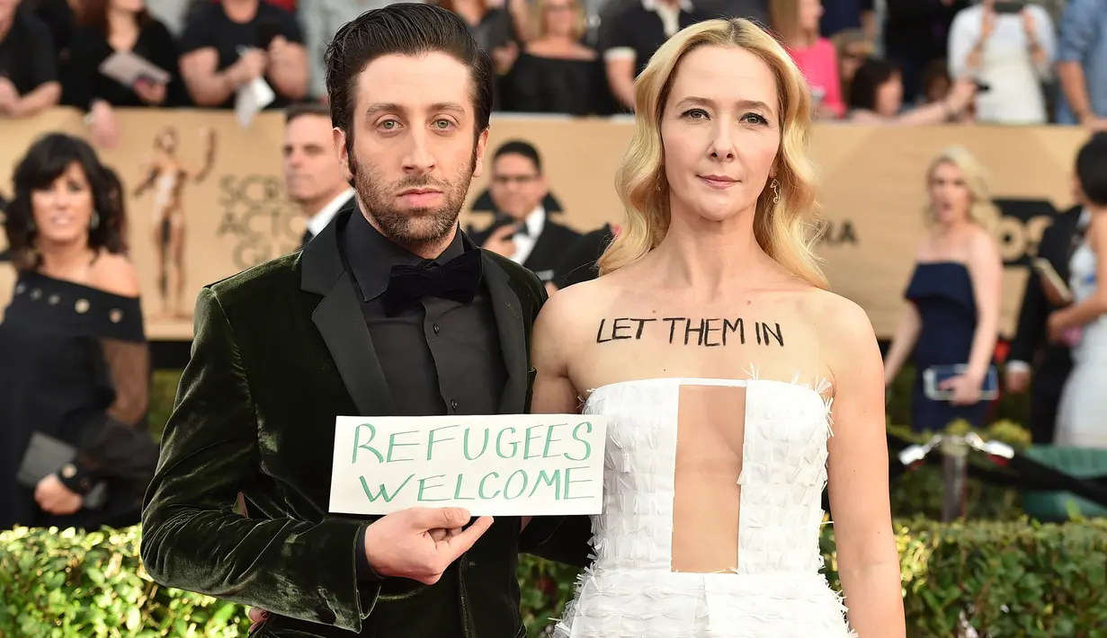 Aktor Simon Helberg dan istri, Jocelyn Towne menarik perhatian di karpet merah Screen Actors Guild (SAG) Awards di Los Angeles, Minggu (29/1). Bintang 'The Big Bang Theory' itu membawa papan bertuliskan 'Refugees Welcome'. (Jordan Strauss/Invision/AP)