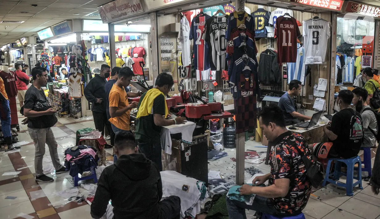 Calon pembeli memilih jersey sepak bola yang akan disablon bertema Piala Dunia 2022 di salah satu kios Blok B Pasar Tanah Abang, Jakarta Pusat, Kamis (8/12/2022). Selain Jakarta, permintaan jasa sablon jersey bertema Piala Dunia 2022 banyak dipesan dari luar Jawa hingga Papua. (merdeka.com/Iqbal S. Nugroho)