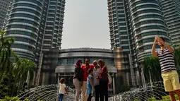 Sejumlah orang memotret di depan Menara Kembar Petronas, Kuala Lumpur, Malaysia, 18 Maret 2016. Kombinasi antara gedung pencakar langit dan situs bersejarah serta perpaduan harmonis beragam budaya semakin memperkaya pesona khas dari Kuala Lumpur. (Xinhua/Chong Voon Chung)