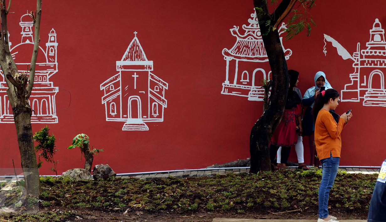Warga melintas di depan gambar tempat ibadah di Lapangan Kebagusan, Jakarta, Rabu (15/2). Jelang menggunakan hak pilihnya pada Pilkada, Ketua Umum PDI-P Megawati Soekarnoputri menggoreskan tinta pada salah satu gambar. (Liputan6.com/Helmi Fithriansyah)