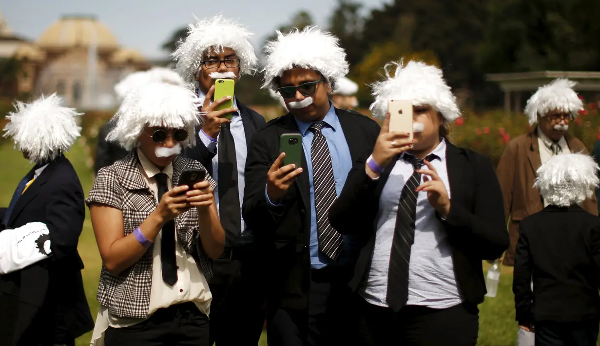 Beberapa orang berpakaian mirip Albert Einstein menggunakan ponsel mereka saat berkumpul untuk mencetak rekor dunia Guinness di LA, California, 27 Juni 2015. Acara ini guna mengumpulkan dana pendidikan anak-anak tunawisma. (REUTERS/Lucy Nicholson)