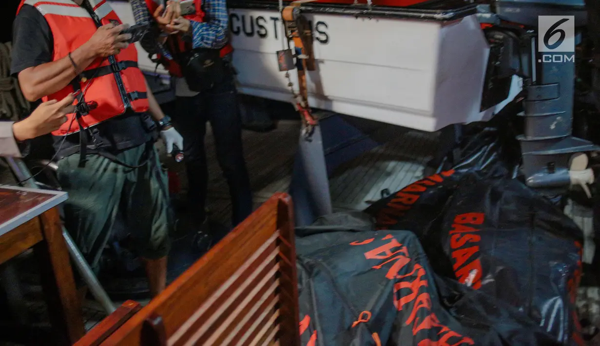 Petugas mengambil gambar kantong berisi jenazah dan serpihan pesawat Lion Air JT 610 yang jatuh di perairan Laut Utara Karawang, Jawa Barat saat dibawa menuju Posko Evakuasi, Tanjung Priok, Jakarta, Senin (29/10) malam. (Liputan6.com/Faizal Fanani)