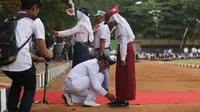 Wakil Bupati Sragen Deddy Endriyatno berjongkok membetulkan ikatan tali sepatu salah satu petugas upacara sambil menahan sakit tangannya. (foto : Liputan6.com/dpwpksjateng/edhie prayitno ige)