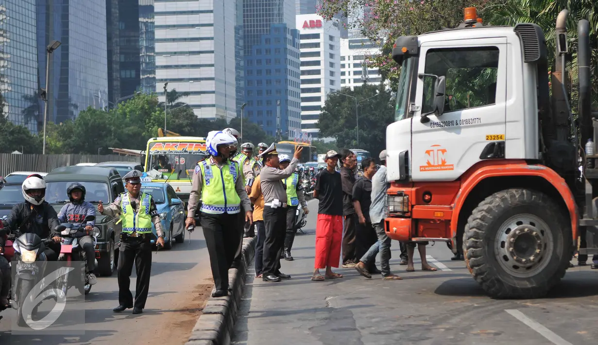 Petugas kepolisian mengatur lalu lintas akibat truk mengalami patah as di Jakarta, Selasa (29/9/2015). Imbas dari truk bermuatan alat berat mengalami patah as itu, Jalan Sudirman mengarah ke Jalan MH Thamrin terpantau padat. (Liputan6.com/Gempur M Surya)