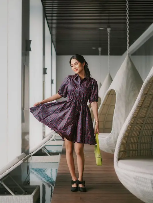 Manisnya penampilan Azizah Salsha pakai shirt dress lengan sesiku berwarna ungu bercorak floral yang manis, dengan panjang di atas lutut. Ia padukan dengan kitten heels hitam dan tas tangan berwarna hijau neon. [Foto: Instagram/azizahsalsha_]