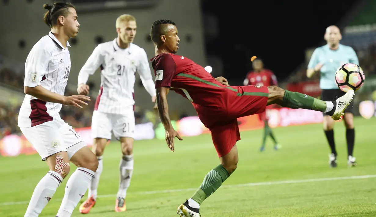 Pemain Portugal, Nani (kanan) berusaha menahan bola saat dihadang para pemain Latvia pada laga Kualifikasi Piala Dunia 2018 di Algarve stadium, Faro (13/11/2016). Portugal menang 4-1. (AFP/Francisco Leong)