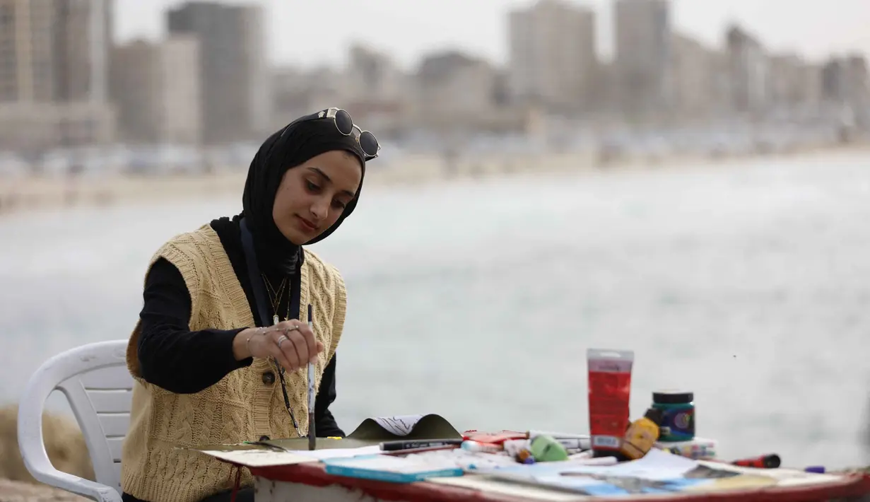 Lokakarya Bernapas dan Melukis menjadikan seni dan budaya untuk membangun kembali kepercayaan diri dan harapan. Tampak dalam foto, seorang perempuan muda melukis di pelabuhan Kota Gaza pada Kamis 12 Februari 2026. (Omar AL-QATTAA/AFP)