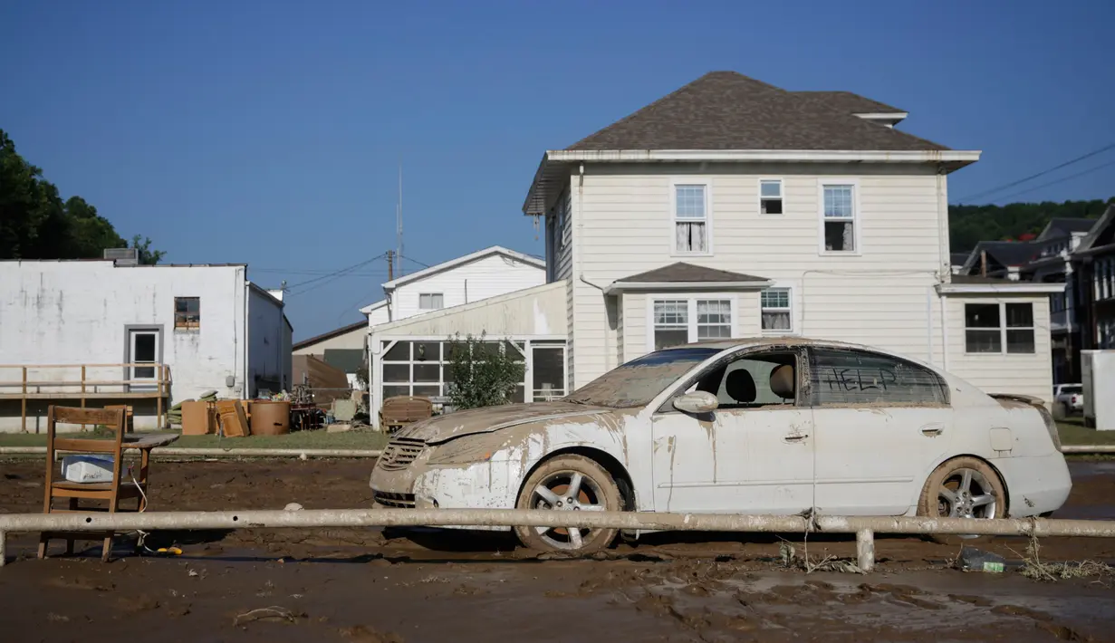 Lumpur menutupi mobil yang terparkir di depan rumah setelah banjir dahsyat di Clendenin, Virginia Barat, Minggu (26/6). Bencana banjir di negara bagian itu disebabkan oleh hujan deras yang tiada henti. (REUTERS/Marcus Constantino)