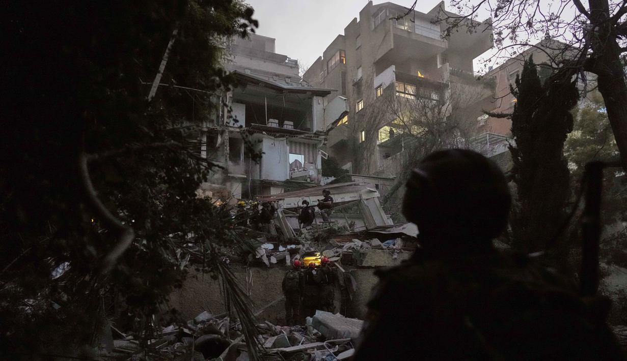 Hantaman rudal Iran menimbulkan kerusakan signifikan pada infrastruktur bangunan setinggi tujuh lantai tersebut. Tampak dalam foto, pasukan keamanan Israel dan tim penyelamat melakukan upaya pencarian korban di tengah reruntuhan bangunan tempat tinggal yang dihantam rudal Iran di Haifa, Israel, Minggu, 5 April 2026. (AP Photo/Ariel Schalit)