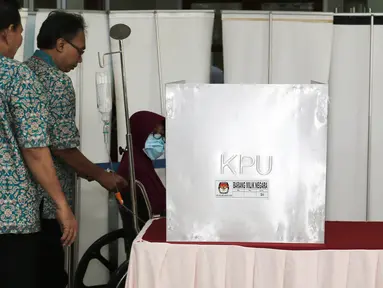 Pasein RSCM Lisa Hartanti dibantu petugas bersiap mencobloskan surat suara saat mengikuti Pilkada DKI 2017 di TPS 15 RSCM, Jakarta, Rabu (15/2/2017). (Liputan6.com/Herman Zakharia)