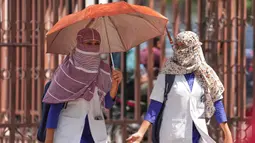 Mahasiswa kedokteran dengan wajah tertutup syal sebagai perlindungan dari terik matahari musim panas, berjalan di Lucknow, India, Rabu 20 Mei 2026. (AP Photo/Rajesh Kumar Singh)