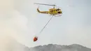 Sebuah helikopter membawa air untuk membantu memadamkan kebakaran yang melanda kawasan Somerset West dekat Cape Town, Afrika Selatan, Rabu (4/1). Kebakaran tersebut telah menghancurkan sebagian wilayah perkebunan tertua di Afsel. (AP Photo / Stefan Smuts)