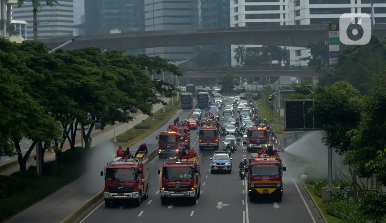 Petugas pemadam kebakaran (Damkar) dengan mobil pemadam melakukan penyemprotan cairan disinfektan di sepanjang jalan Thamrin-Sudirman, Jakarta, Sabtu (28/3/2020). Penyemprotan dilakukan untuk meminimalisir penyebaran COVID-19 di ruang udara dan ruas jalan. (merdeka.com/Imam Buhori)