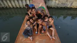 Keseruan anak-anak berfoto saat bermain dan mandi di anak Kali Ciliwung, Jakarta, Rabu (13/7). Bersihnya kali yang berada di Ibu Kota itu dimanfaatkan anak-anak sekitar untuk berenang sambil mengisi waktu libur sekolah. (Liputan6.com/Immanuel Antonius)