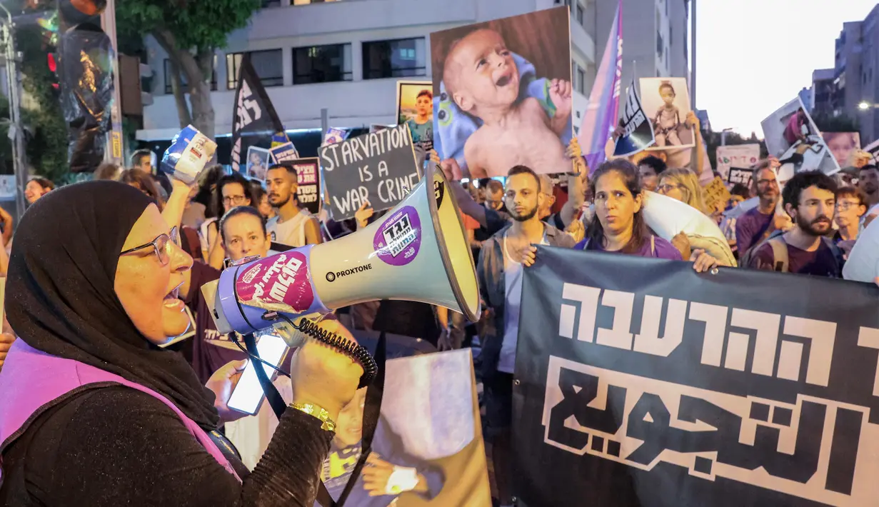 Seorang wanita berbicara melalui megafon ketika para aktivis Israel berbaris dengan membawa karung-karung tepung menuju markas besar Kementerian Pertahanan Israel di Tel Aviv pada 22 Juli 2025. (Jack GUEZ/AFP)
