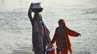 Wanita yang terkena banjir membawa air minum dalam wadah setelah melarikan diri dari banjir yang melanda rumah mereka setelah hujan lebat di daerah Sohbatpur di distrik Jaffarabad di provinsi Balochistan (29/8/2022). (AFP/Fida Hussain)