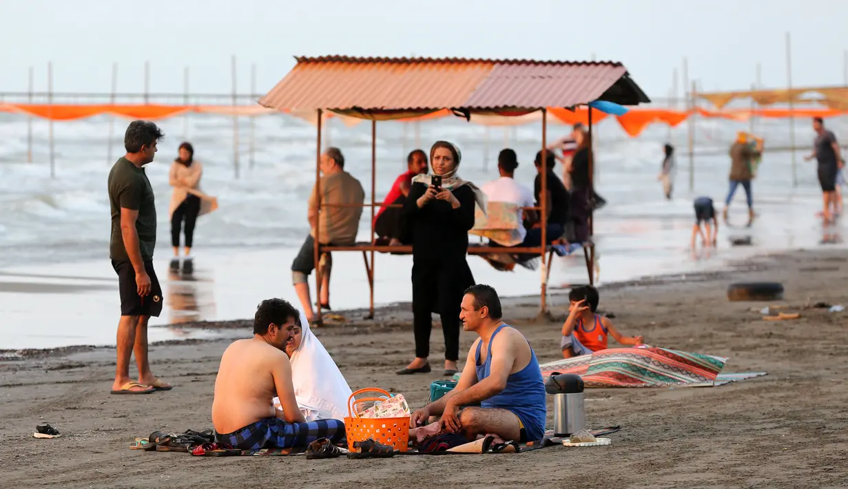 Warga Iran beristirahat sambil menikmati suasana di pantai di kota Laut Kaspia, Izadshahr, provinsi Mazandaran utara (8/7/2019). Laut Kaspia terletak di antara Eropa dan Asia, di sebelah barat dan barat-daya pegunungan Ural. (AFP Photo/Atta Kenare)