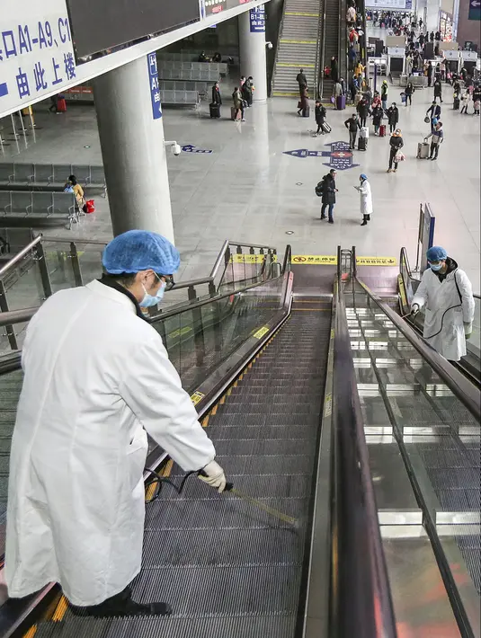 Petugas menyemprotkan cairan disinfektan ke eskalator di Stasiun Kereta Api Yingtan di Nanchang di Provinsi Jiangxi Tengah, China (22/1/2020). China telah melarang kereta api dan pesawat terbang meninggalkan kota yang menjadi wabah virus corona pada 23 Januari 2020. (AFP Photo/STR)