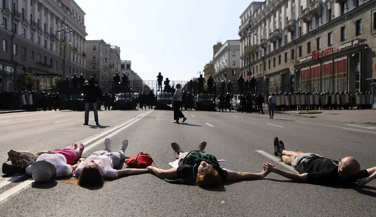 Para pengunjuk rasa berbaring di depan polisi antihuru-hara yang memblokir demonstrasi pendukung oposisi Belarusia di Minsk, Belarusia, Minggu (30/8/2020). Puluhan ribu demonstran berkumpul untuk menuntut agar Presiden Belarusia Alexander Lukashenko mengundurkan diri. (AP Photo)