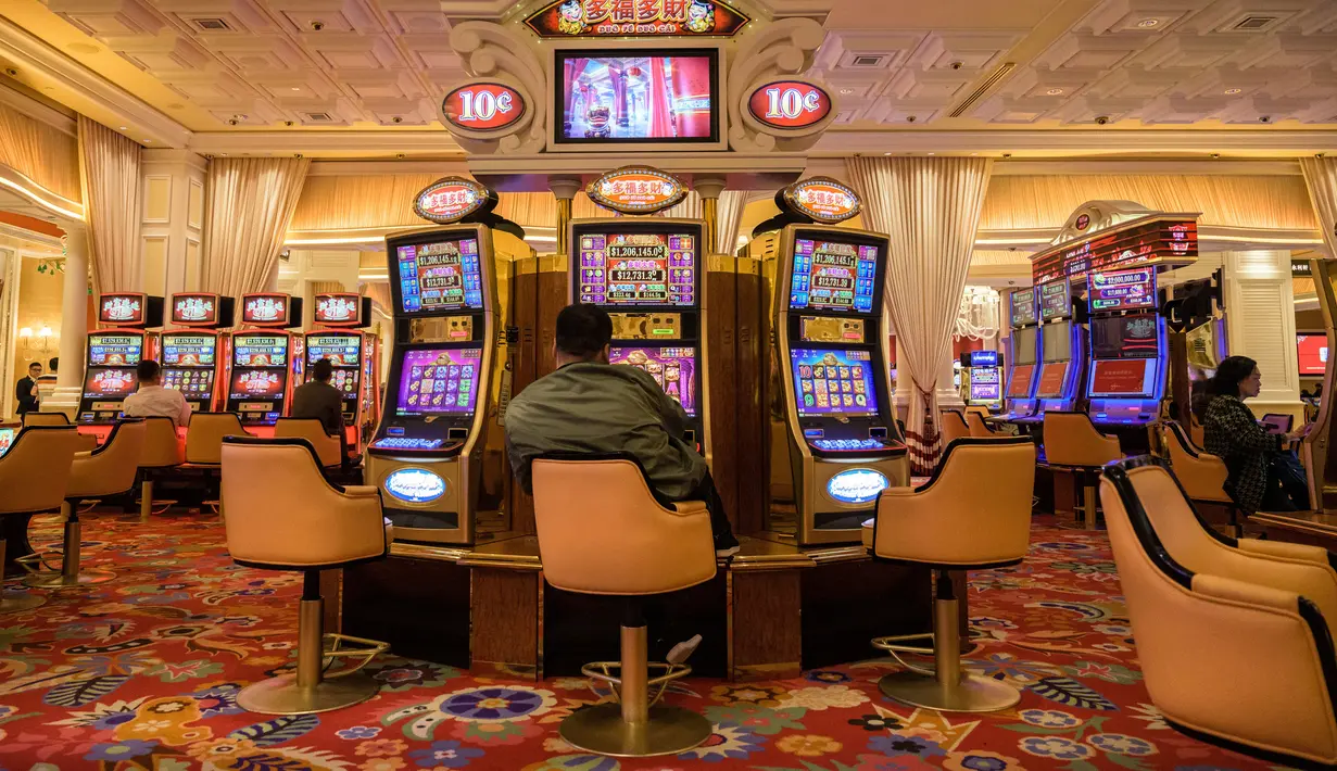 Pengunjung bermain mesin slot di sebuah resor di Macau, 5 Maret 2019. Macau merupakan kota judi terbesar di Asia. (Anthony Wallace/AFP)
