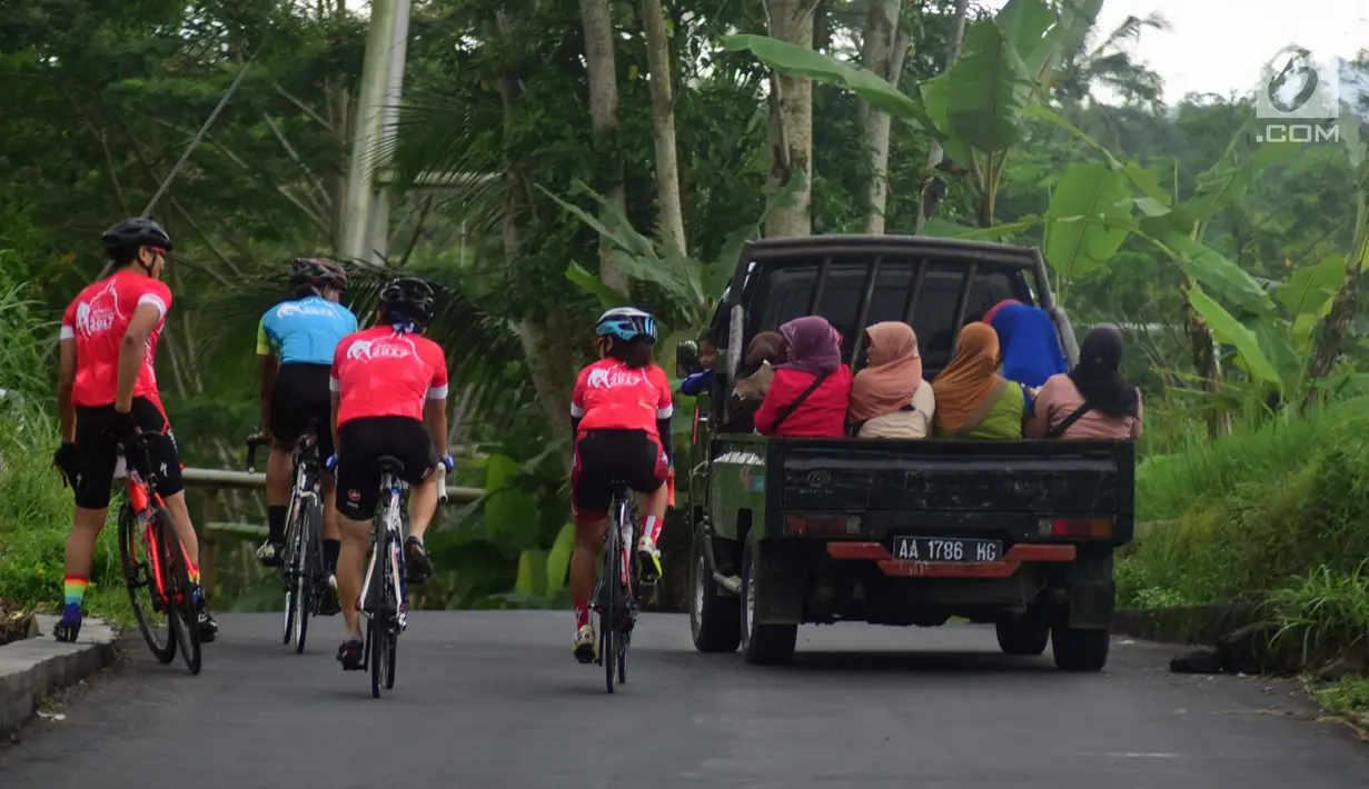 Sejumlah peserta mengayuh bersebelahan dengan warga yang menaiki mobil pickup saat mengikuti BTN Tour de Borobudur XVII di Jawa Tengah (12/11). (Liputan6.com/Gholib)