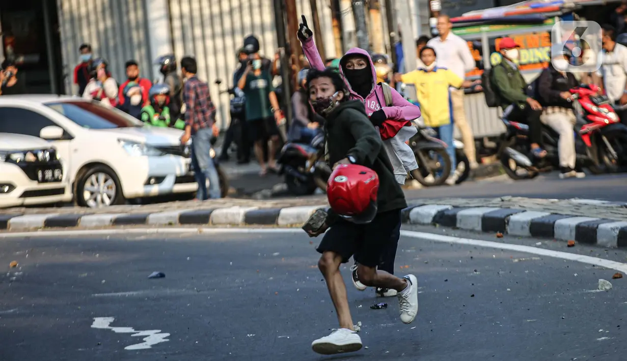 Massa melemparkan batu ke arah polisi saat bentrok di kawasan Pejompongan, Jakarta, Rabu (7/10/2020). Belum bisa dipastikan apakah aksi tersebut berkaitan dengan isu aksi penolakan pengesahan UU Omnibus Law Cipta Kerja. (Liputan6.com/Faizal Fanani)