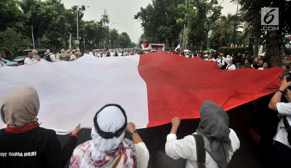 Massa GJI membentangkan bendera Merah Putih raksasa saat menggelar aksi menuntut Gubernur DKI Jakarta Anies Baswedan untuk mencabut izin penyelanggaraan Reuni 212 di depan Balai Kota, Jakarta, Kamis (29/11). (Merdeka.com/Iqbal S. Nugroho)