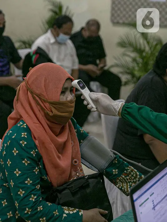 Tenaga kesehatan mengukur suhu tubuh tenaga pendidik sebelum vaksin COVID-19 di SMP 216, Jakarta Pusat, Selasa (6/4/2021). Menurut Menteri Kesehatan Budi Gunadi Sadikin, pemerintah akan memprioritaskan kelompok lansia dan juga tenaga pengajar dalam vaksinasi kali ini. (Liputan6.com/Faizal Fanani)