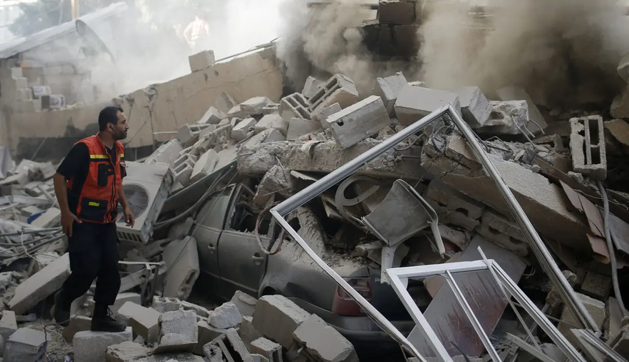 Seorang petugas pemadam kebakaran Palestina berupaya mencari korban selamat diantara reruntuhan puing rumah yang hancur akibat serangan udara militer Israel di Gaza, (31/7/2014). (REUTERS/Mohammed Salem)