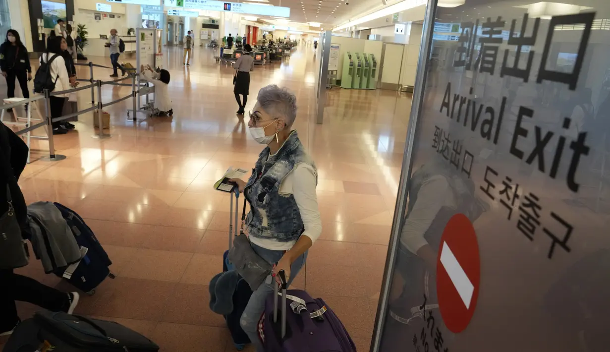Salah satu wisatawan  asing berjalan setibanya di Bandara Internasional Haneda, Tokyo, Selasa (11/10/2022). Jepang termasuk negara yang mempertahankan beberapa tindakan perbatasan paling ketat di antara negara-negara ekonomi utama sejak awal pandemi. (AP Photo/Eugene Hoshiko)