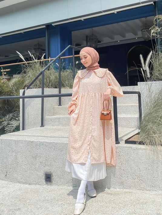 Tampil lebih fresh sambut tahun baru 2022 dengan padu padan tunik warna orange dan rok plisket warna putih. Untuk hijab, kamu bisa pilih warna cream atau nude (Instagram/liza.rosalita).