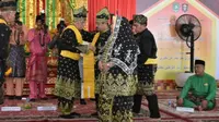 Bupati Bengkalis Amril Mukminin (dipakaikan selempang) ketika menerima gelar adat dari LAM Kabupaten Bengkalis. (Liputan6.com/Istimewa/M Syukur)