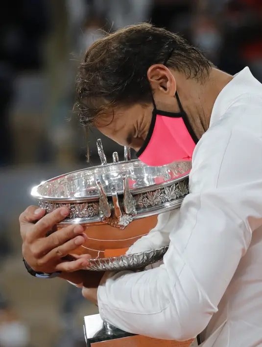 Petenis Rafael Nadal memegang trofi saat merayakan kemenangannya atas Novak Djokovic pada final Prancis Terbuka 2020 di Stadion Roland Garros, Paris, Prancis, Minggu (11/10/2020). Dengan kemenangan ini, Nadal menyamai rekor Roger Federer dengan meraih 20 gelar Grand Slam. (AP Photo/Christophe Ena)