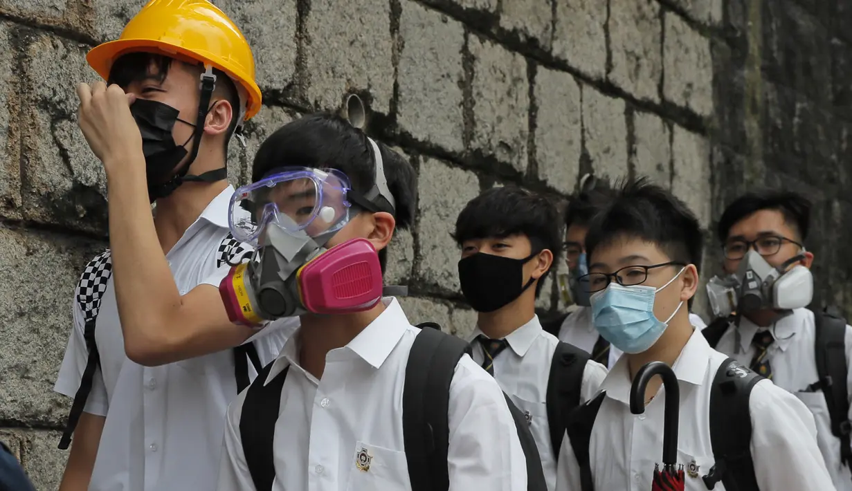 Para siswa sekolah mengenakan topeng dan helm berjalan di luar St. Paul's College selama protes di Hong Kong, Selasa (3/9/2019). Puluhan ribu siswa di Hong Kong memprotes terhadap gerakan anti-pemerintah. (AP Photo/Kin Cheung)