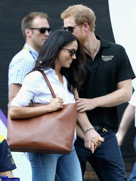 Ini merupakan tampilan perdananya di depan umum bersama sang kekasih, Pangeran Harry saat hadir di Invictus Games. Meghan berpakaian kasual hanya dengan celana jeans dan kemeja putih.  (AFP/Chris Jackson)
