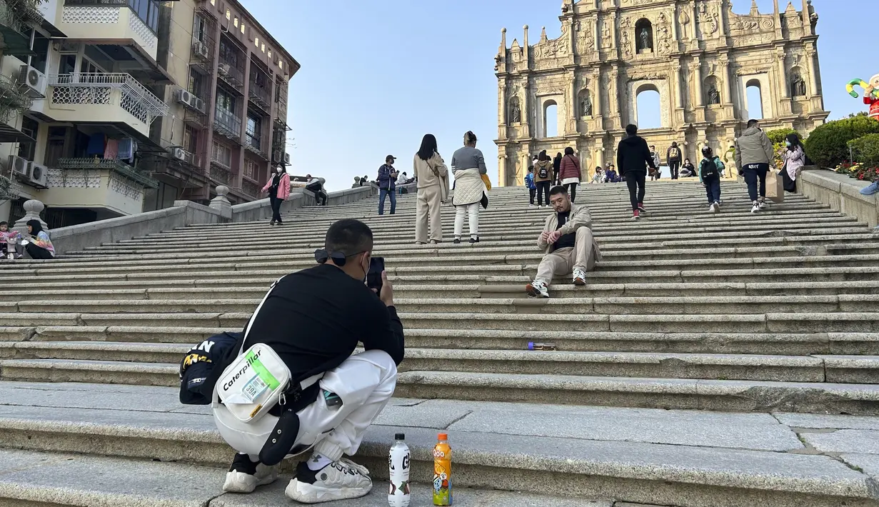 Turis mengambil foto di situs bersejarah Reruntuhan St. Paul di Makau pada 28 Desember 2022. Pelonggaran pembatasan perbatasan setelah pemerintah China membatalkan strategi “nol Covid-19” pada awal Desember 2022 diperkirakan akan secara luas meningkatkan ekonomi yang digerakkan oleh pariwisata. (AP Photo/Kanis Leung)