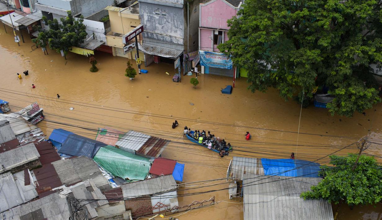 Warga mengungsi menggunakan perahu di kota Dayeuhkolot yang terendam banjir di Bandung pada 12 Januari 2024. (TIMUR MATAHARI/AFP)