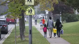 Para murid dan orang tuanya tiba di sebuah sekolah di Mississauga, Ontario, Kanada (9/9/2020). Beberapa sekolah di Ontario dibuka kembali pada Rabu (9/9), menawarkan kombinasi kelas tatap muka dan pembelajaran daring (online) bagi para murid. (Xinhua/Zou Zheng)