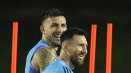 Lionel Messi (kanan) dan Leandro Paredes tertawa selama sesi latihan di Stadion Universitas Qatar, Doha, Qatar, Senin (5/12/2022). Skuad La Albiceleste akan bertemu Belanda di Stadion Lusail pada Sabtu (10/2/2022). (AP Photo/Jorge Saenz)